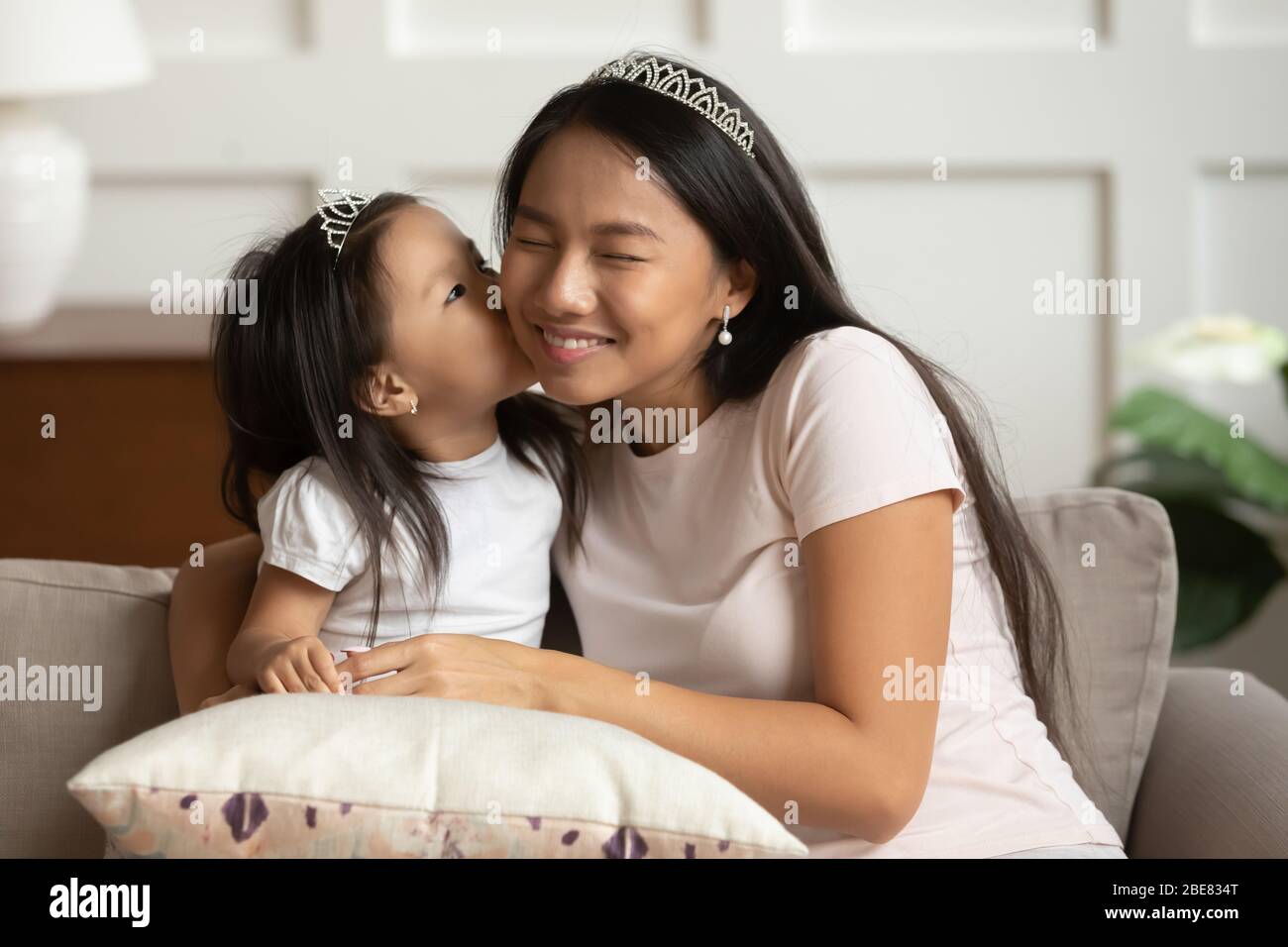 Wenig asiatisch Tochter küsst auf Wange junge Mutter Stockfoto