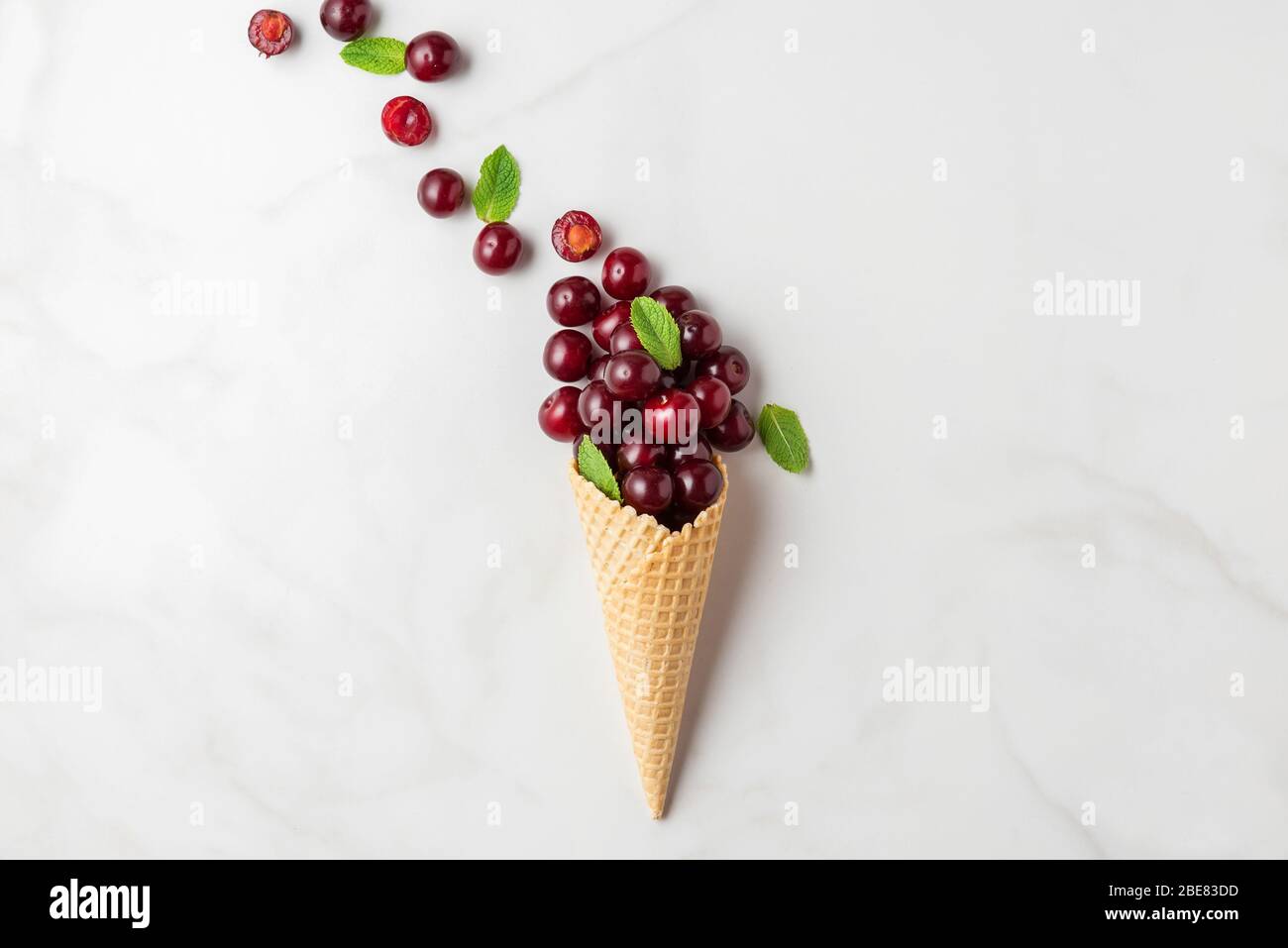 Zusammensetzung der Lebensmittel. Frische Sommer Kirsche Beeren mit Minze in Waffel Eis-Kegel auf weißem Hintergrund. Draufsicht. Flach legen Stockfoto