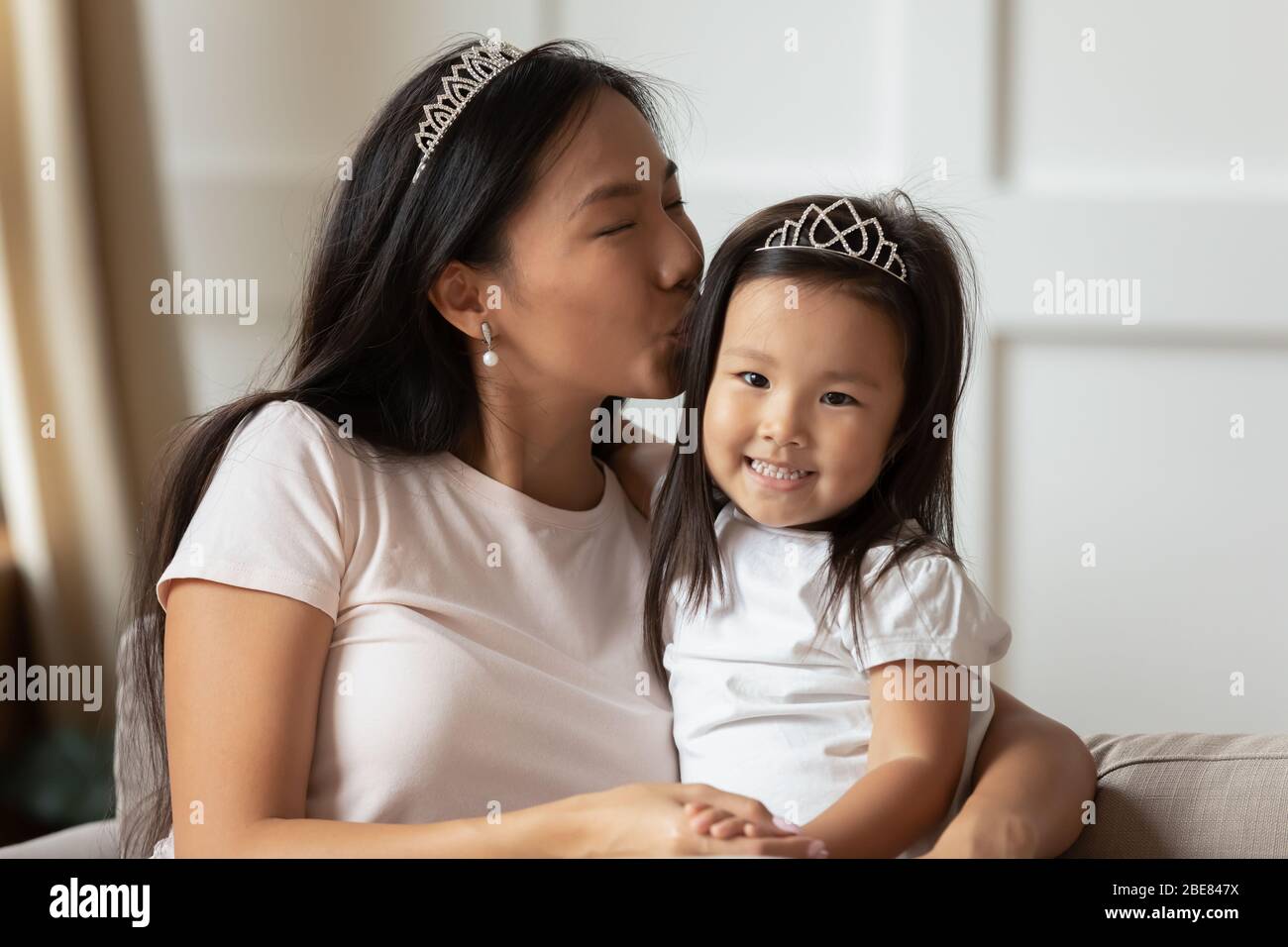 Asiatische Mutter küsst wenig cutie Tochter sitzen auf Couch Stockfoto