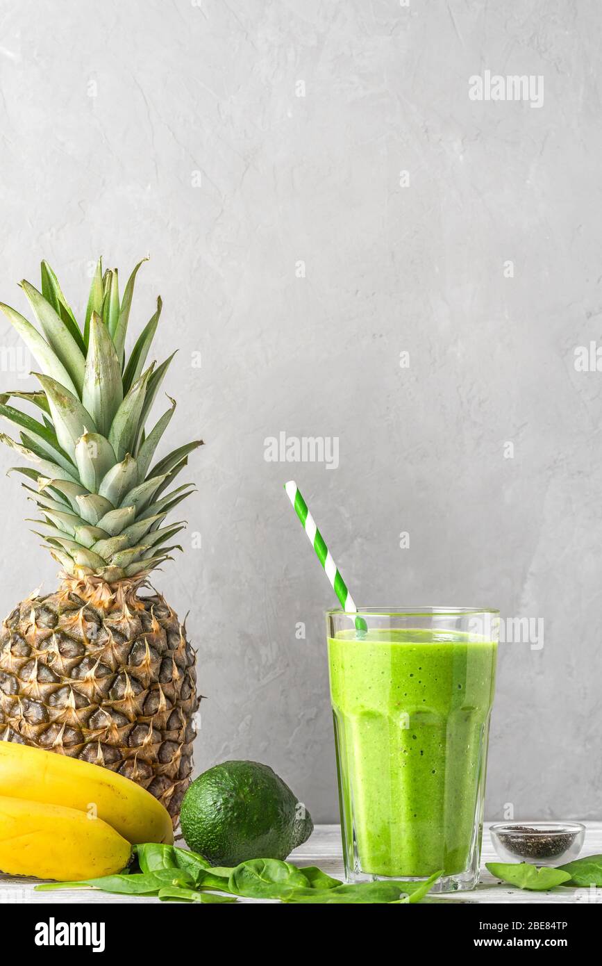 Rohes veganes gesundes Getränk. Grüner Smoothie Detox in einem Glas mit einem Stroh aus Spinat, Ananas, Avocado und Chia Samen. Vertikale Ausrichtung mit CO Stockfoto