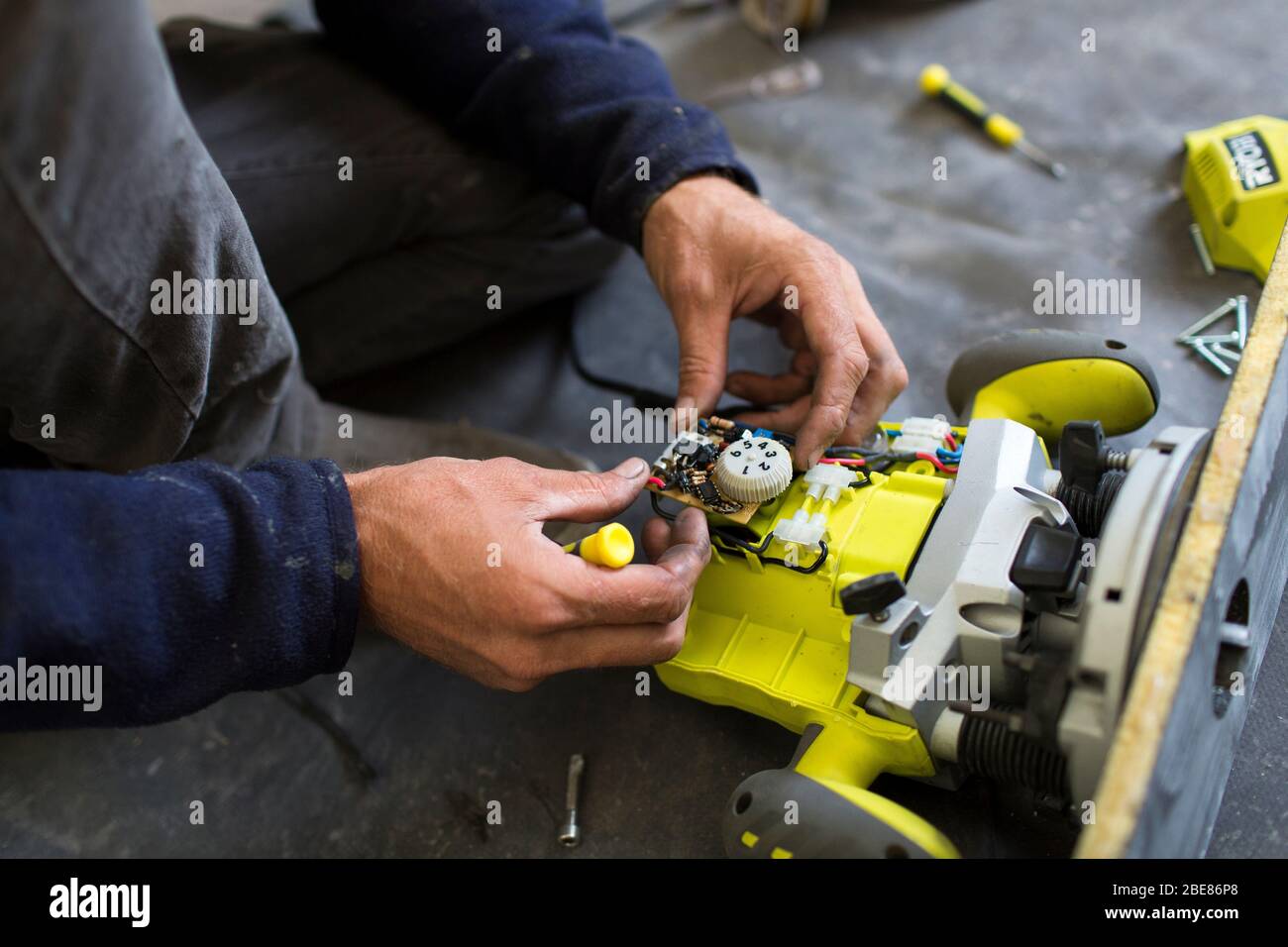 Ein Bootsbauer zerlegt einen Ryobi-Router, um eine defekte Verbindung zu reparieren. Gesetze über das Recht auf Reparatur verändern die Gewohnheiten der Menschen. Etel Frankreich Stockfoto