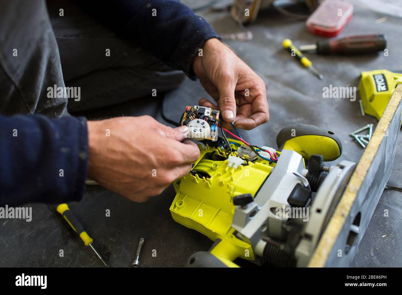 Ein Bootsbauer zerlegt einen Ryobi-Router, um eine defekte Verbindung zu reparieren. Gesetze über das Recht auf Reparatur verändern die Gewohnheiten der Menschen. Etel Frankreich Stockfoto