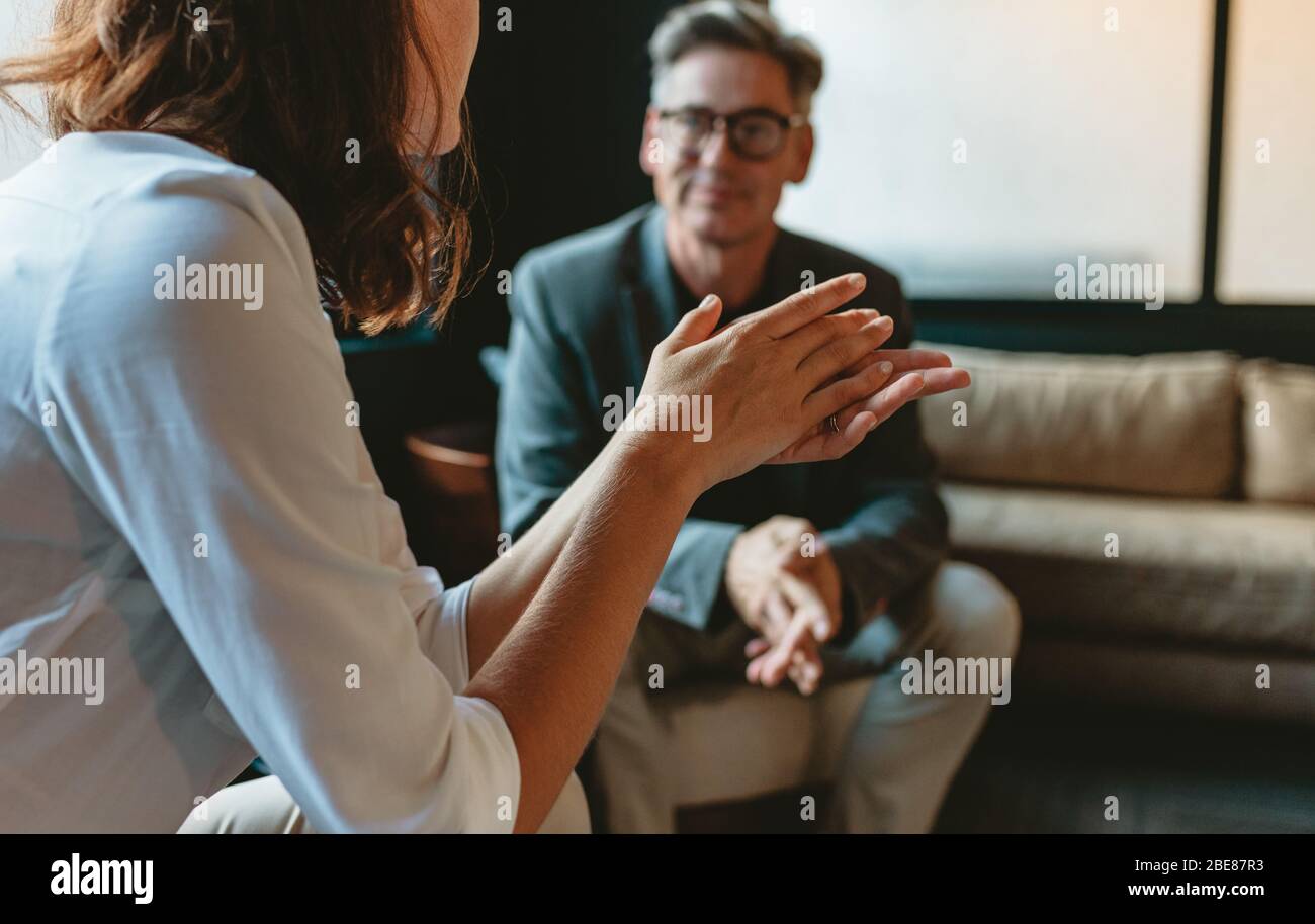Zwei Geschäftsleute diskutieren in der Bürolounge. Geschäftsfrau im Gespräch mit einem männlichen Kollegen in der Bürolobby. Stockfoto