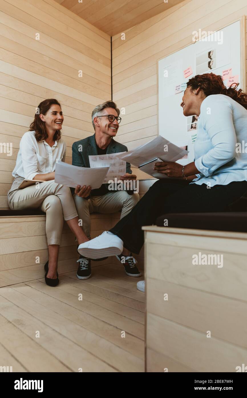 Designerin, die ihrem Team bei der Besprechung neue Ideen zum Projekt gibt. Geschäftsleute diskutieren über neue Geschäftsprojekten im Büro. Stockfoto