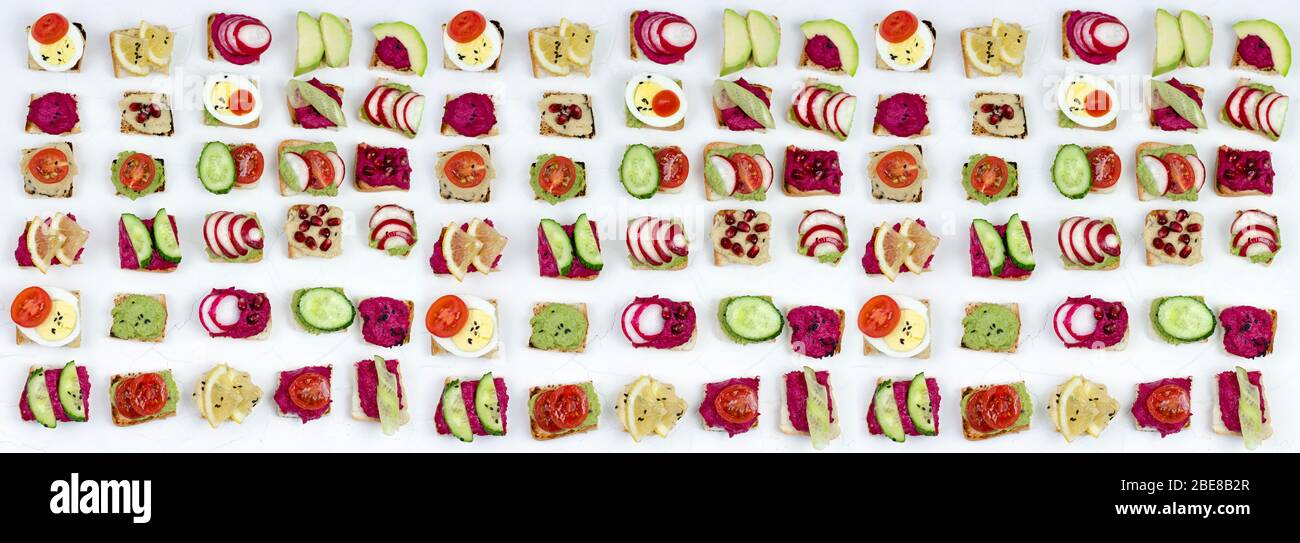 Banner. Verschiedene Bruschetta Sandwiches mit Rübenhummus, Guacamole, verschiedene Gemüse. Vegetarisches Helsifood-Konzept. Sommernack. Essen patern auf Stockfoto