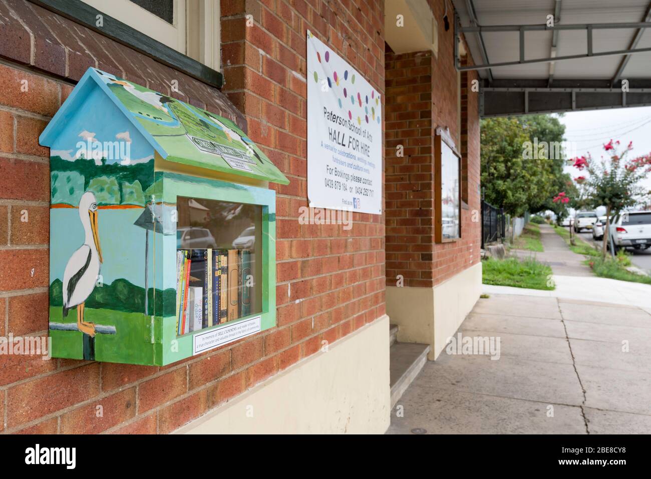 Eine farbenfrohe Mini-Straßenbibliothek, die an der Außenseite des Gebäudes der Paterson School of the Arts im ländlichen New South Wales, Australien, angebracht ist Stockfoto