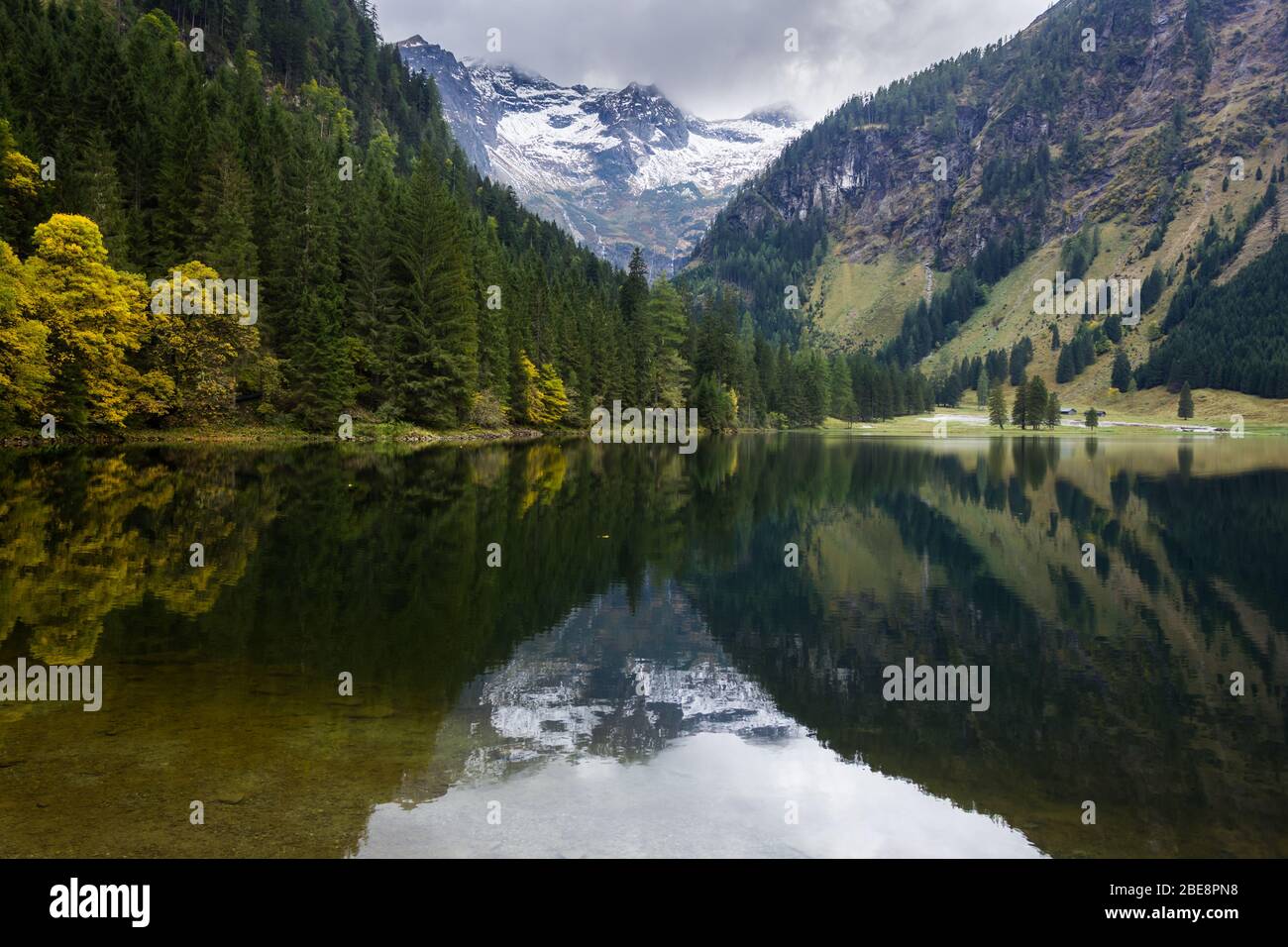Schöner Alpensee mit Spiegelung und umgeben von schneebedeckten Bergen Stockfoto