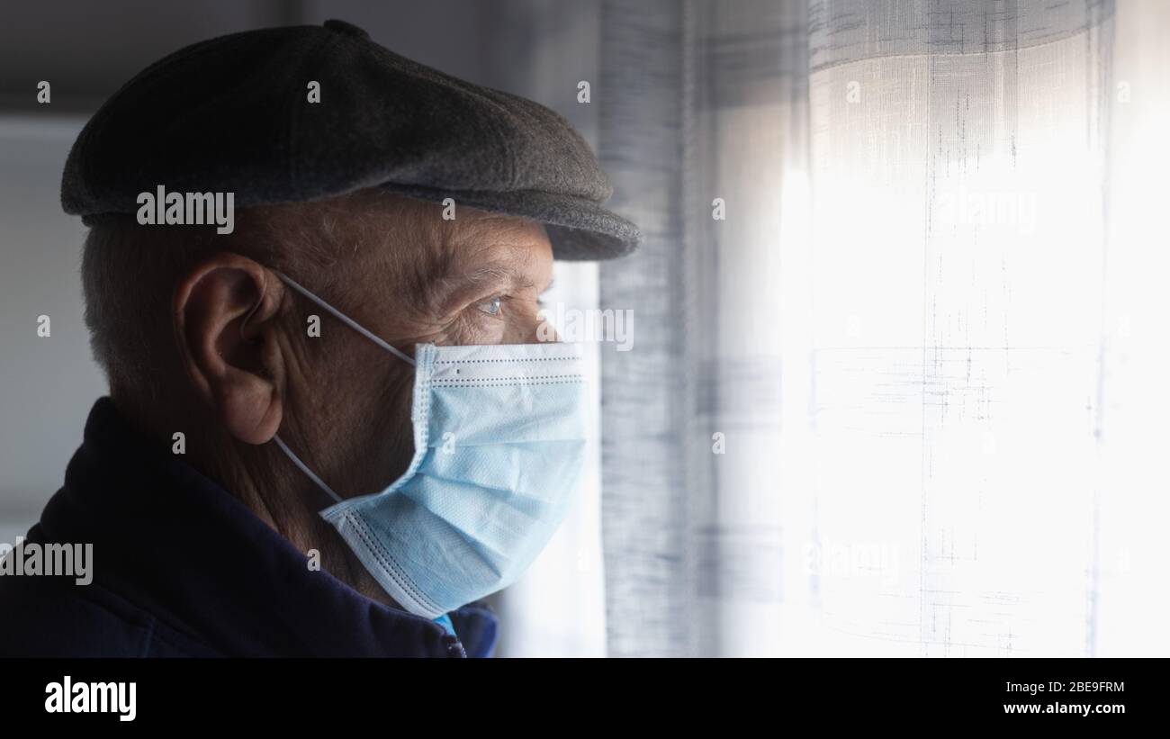 Italienischer alter Mann, der nach der Quarantäne in Italien aus dem Fenster schaut Stockfoto