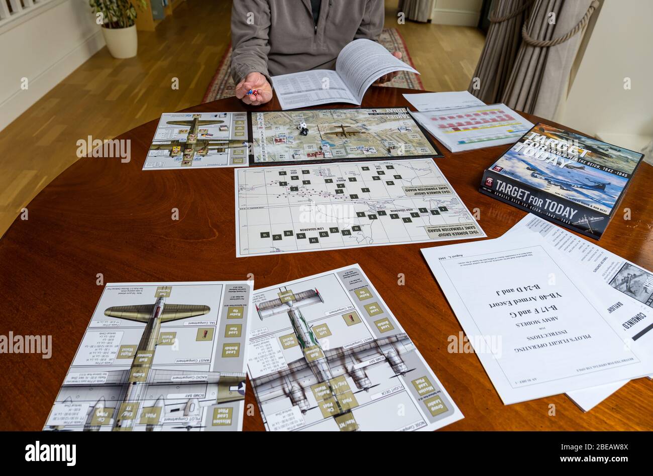 Senior Mann spielt ein Spieler Solitaire Krieg Brettspiel namens Target for Today auf Esstisch in Hause, Großbritannien Stockfoto