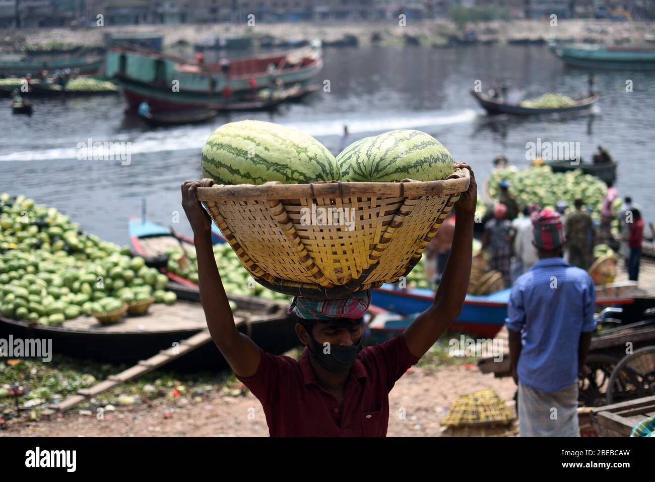 Arbeiter aus Bangladesch entladen während einer von der Regierung auferlegten Blockierung Wassermelonen an einem Dock als vorbeugende Maßnahme gegen das COVID-19-Coronavirus in DH Stockfoto