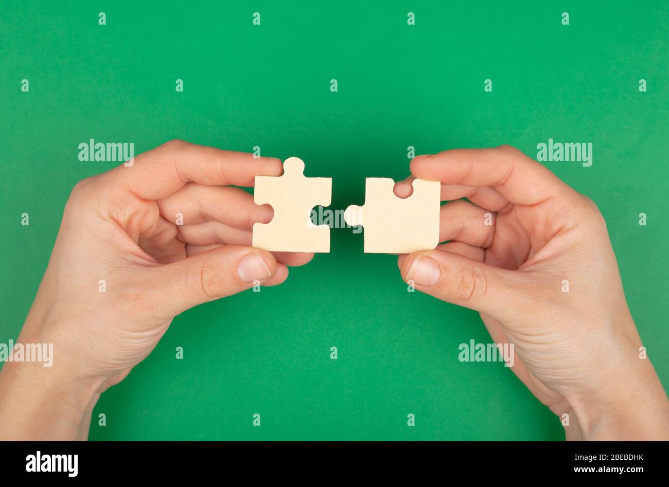 Gelöst Problem, Puzzle von Puzzles in den Händen auf einem grünen Hintergrund. Stockfoto