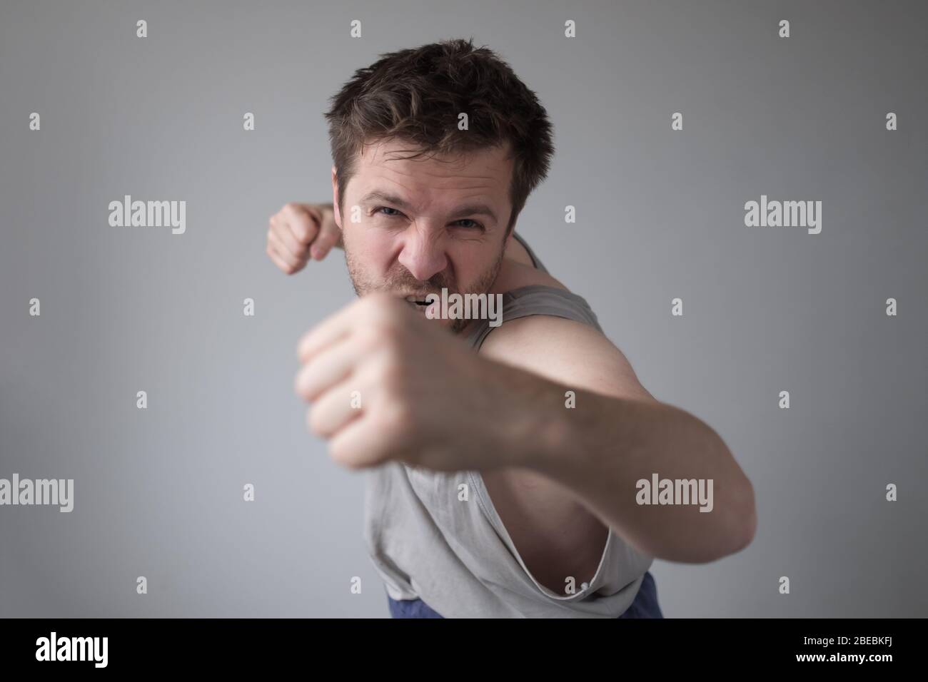 Aggressiver Mann zeigt seine Faust. Häusliche Gewalt und Belästigung während des Aufenthalts wegen Quarantäne. Studioaufnahme Stockfoto