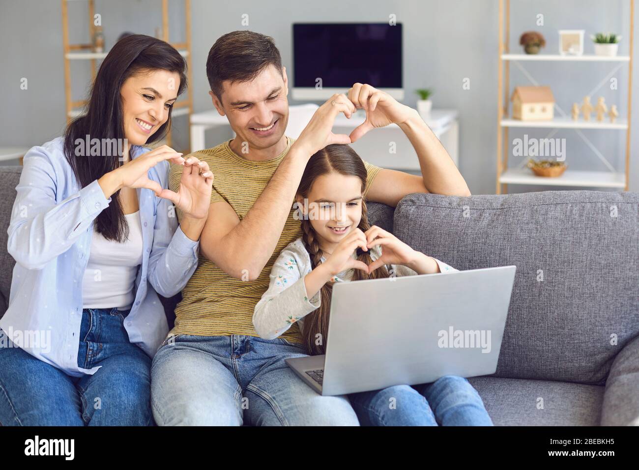 Online-Video-Chat online. Familie hält die Hände in Form eines Herzens willkommen winken Freunde mit Laptop zu Hause. Stockfoto