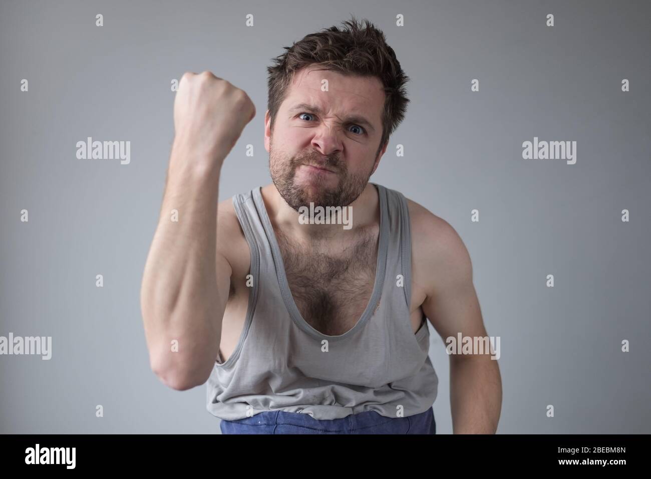 Aggressiver Mann zeigt seine Faust. Häusliche Gewalt und Belästigung während des Aufenthalts wegen Quarantäne. Studioaufnahme Stockfoto