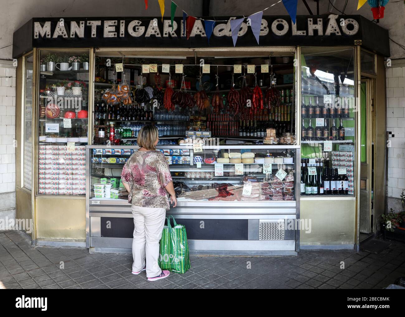 Eine Frau wartet vor einem traditionellen Manteigaria-Marktstand in Porto, der zweitgrößten Stadt Portugals. Stockfoto