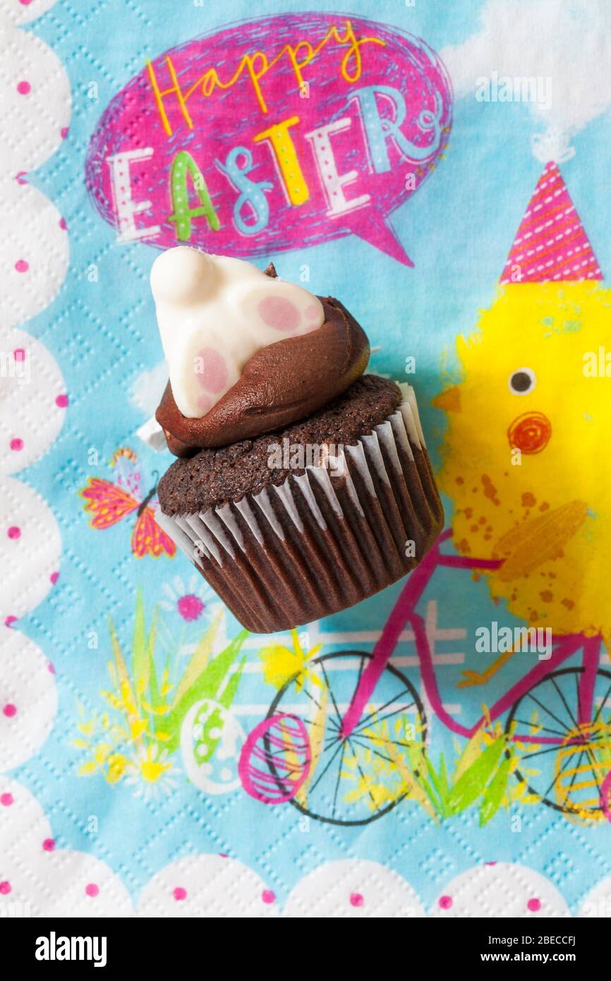 M&S Easter Cupcake auf Serviette Serviette Serviette - Mini-Schokolade Cupcakes mit Schokolade Buttercreme und Ostern Dekorationen - Osterhasen Füße Pfoten Stockfoto