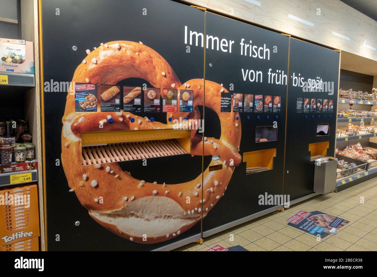 Automatische Brot-, Mini-Pizza-, Brezel- und Croissant-Maschine (Backwaren) in einem Aldi Süd Supermarkt in Salzburg, Österreich. Stockfoto