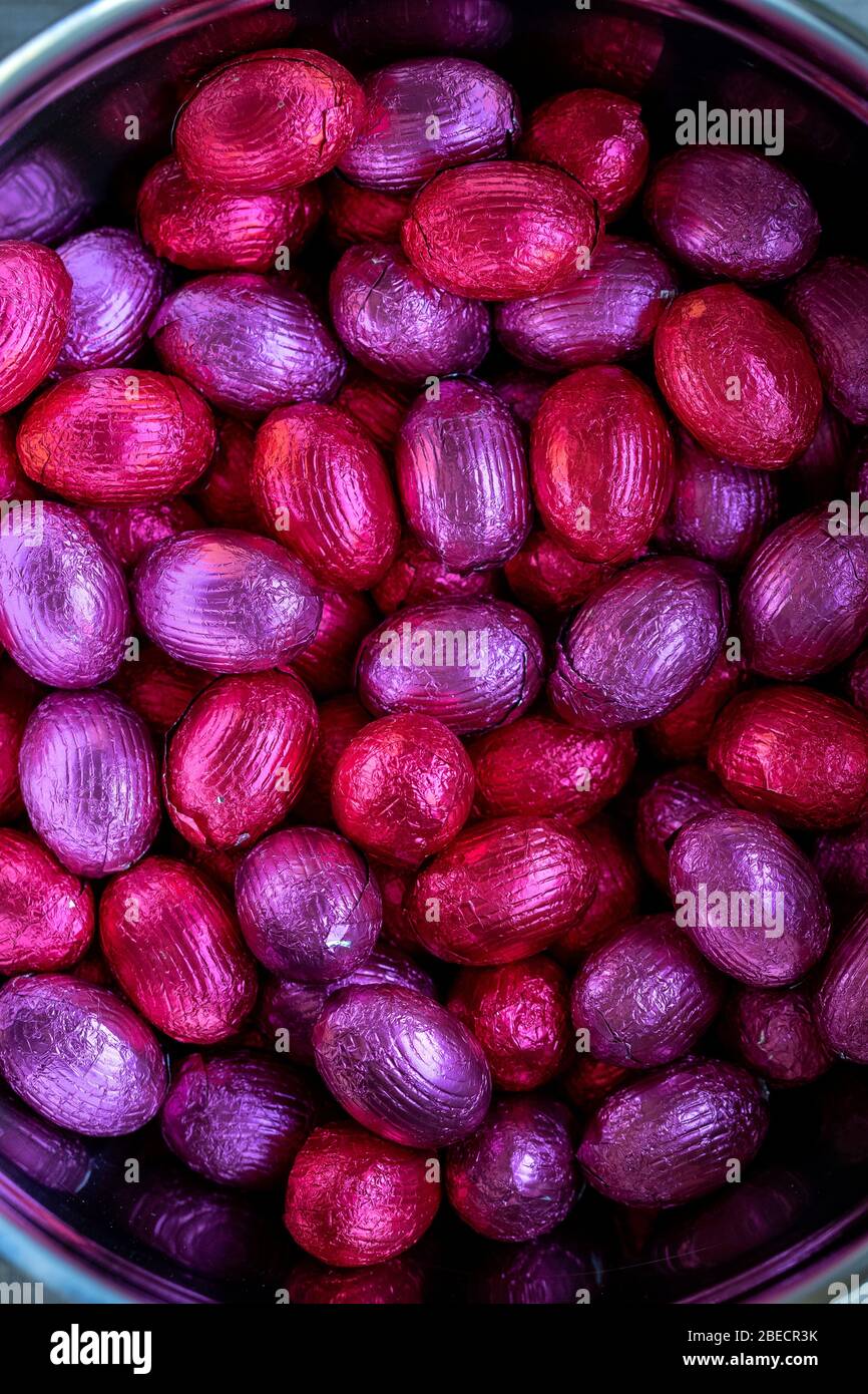 Ein oben unten Nahaufnahme Porträt eines Bündels von bunten Schokolade ostereier in Zinnfolie gewickelt liegen übereinander liegend in einem Metalltopf. Bereit t Stockfoto