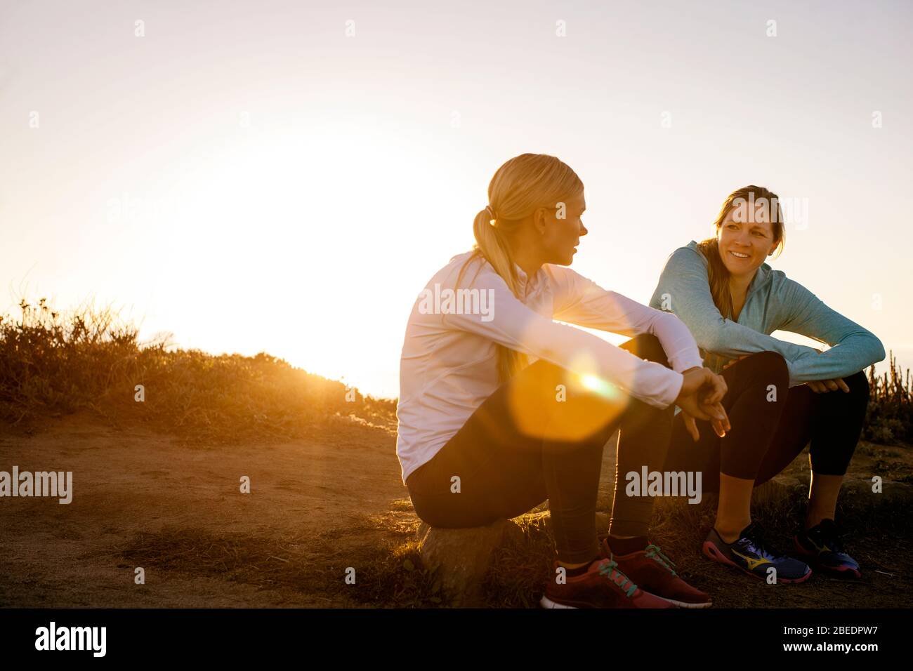 Zwei junge Frauen machen eine Pause vom Laufen bei Sonnenuntergang Stockfoto