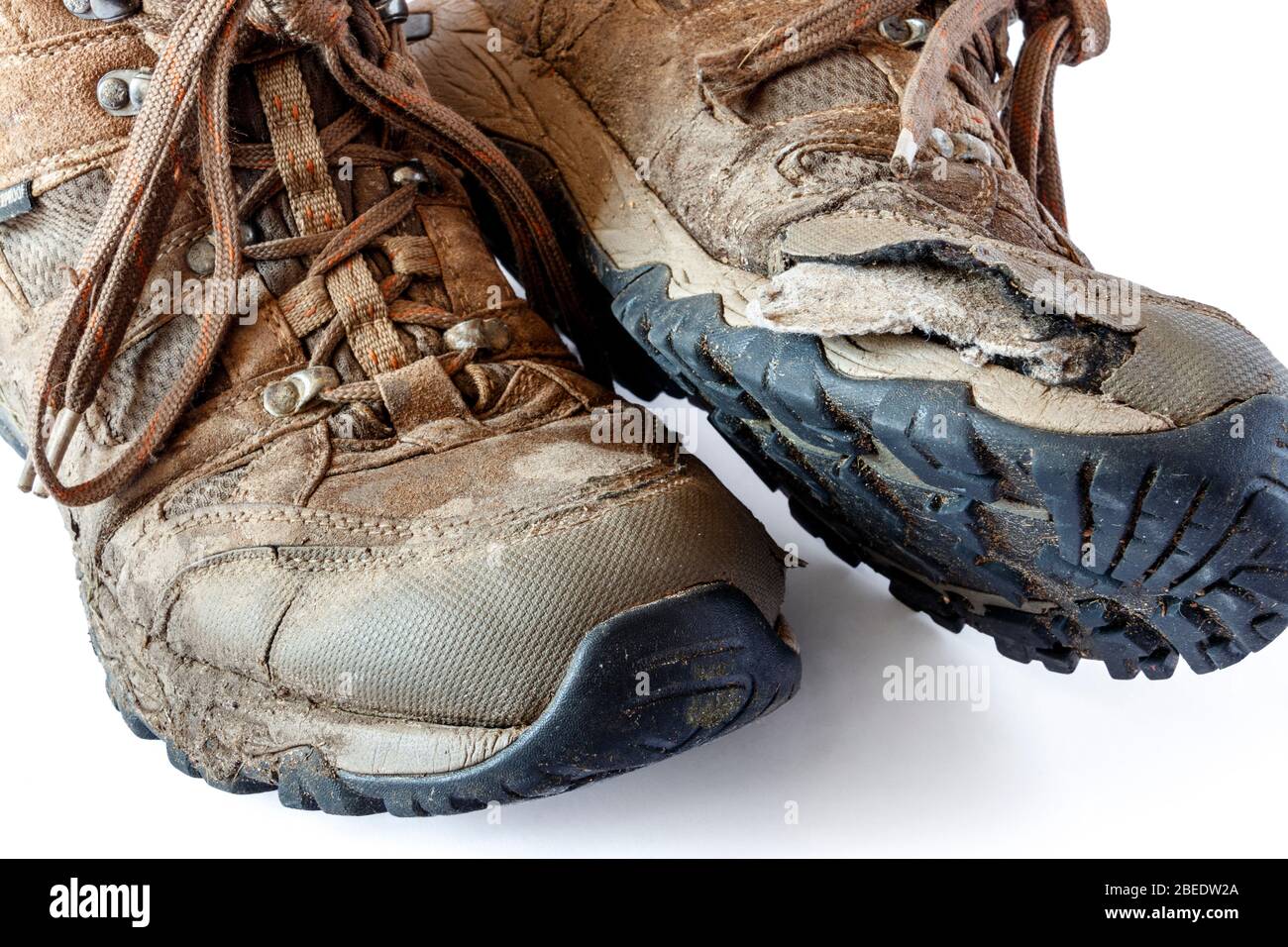 Ein Paar abgenutzte, gespaltene und schlammige Wanderschuhe auf weißem Hintergrund Stockfoto