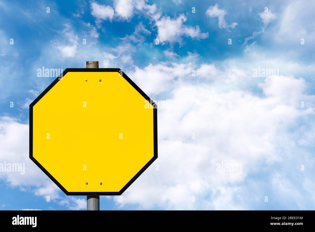 Gelbe achteckige Straßenschild gegen blauen Himmel Stockfoto
