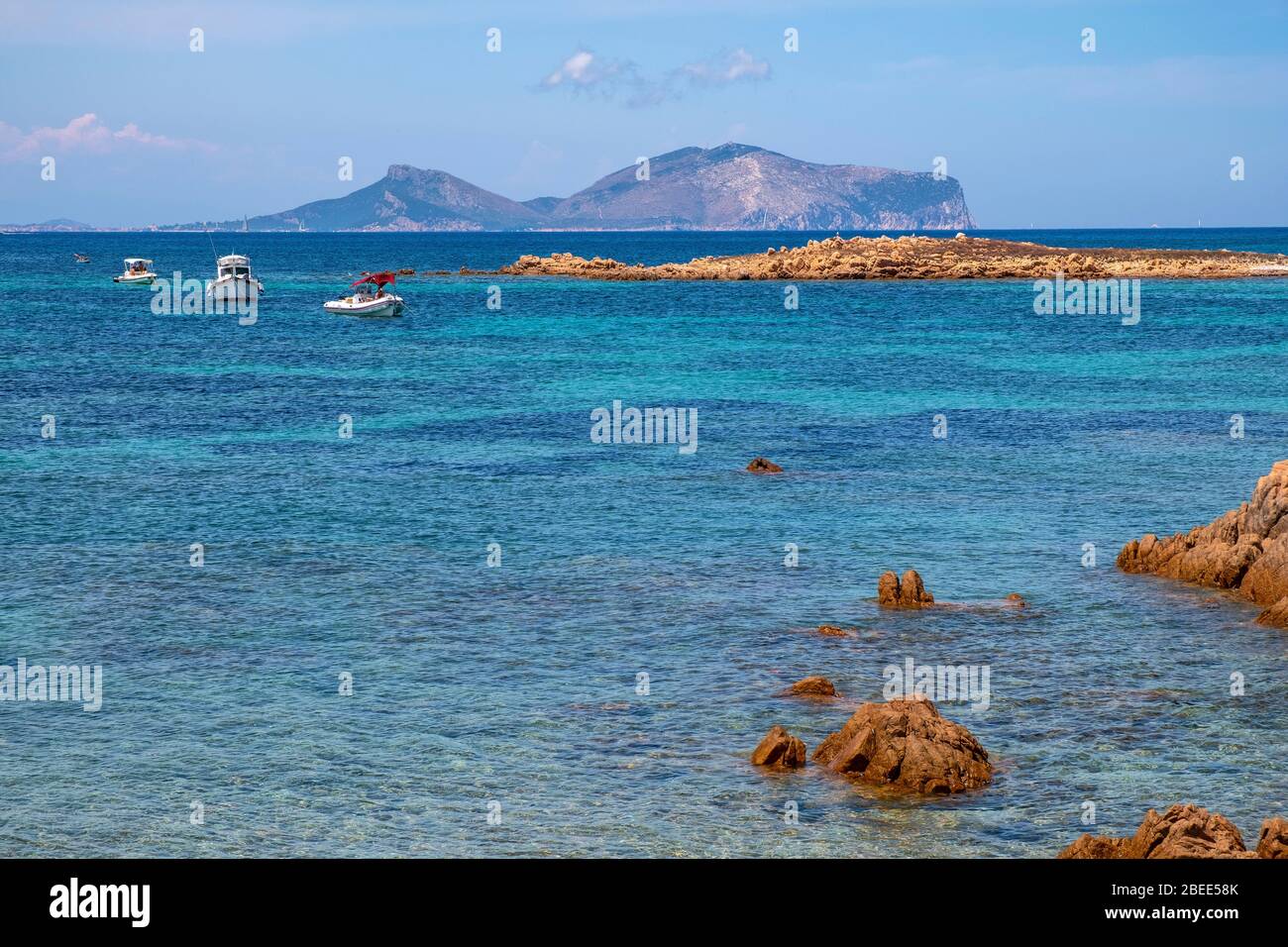 Tavolara, Sardinien / Italien - 2019/07/18: Tyrrhenisches Meer mit Yachten vor der Küste Isola Tavolara mit Capo Figari Kap, Monte Ruju Gipfel Stockfoto