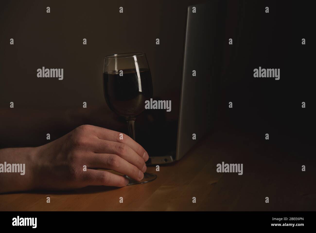 Alkohol trinken - Wein während der Arbeit zu Hause. Laptop und Hand halten Weinglas Stockfoto