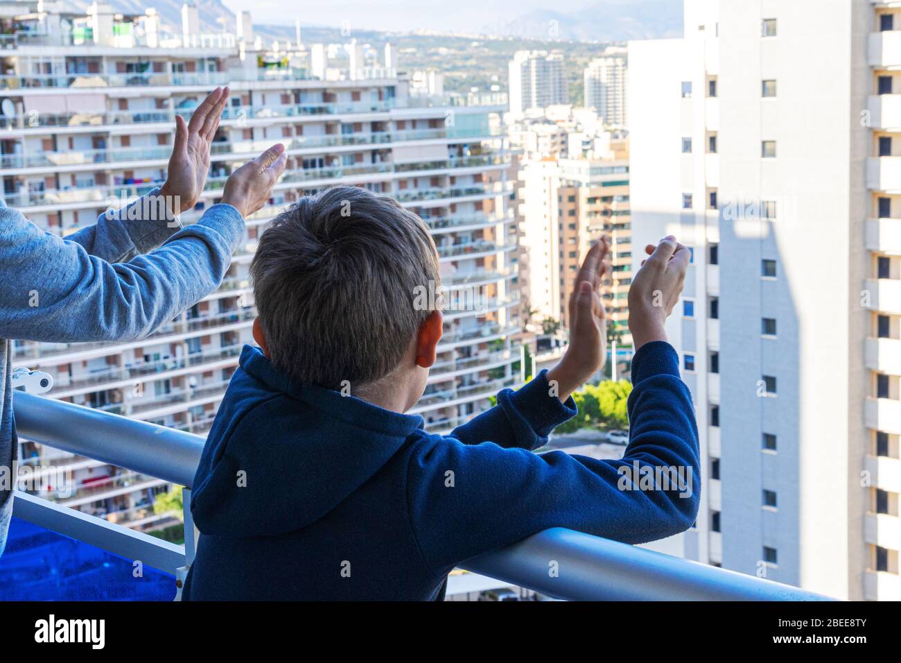 Die Familie lobt das medizinische Personal vom Balkon. Menschen klatschen auf Balkons und Fenstern, um die Gesundheit der Mitarbeiter während der Coronavirus Pandemie zu unterstützen Stockfoto