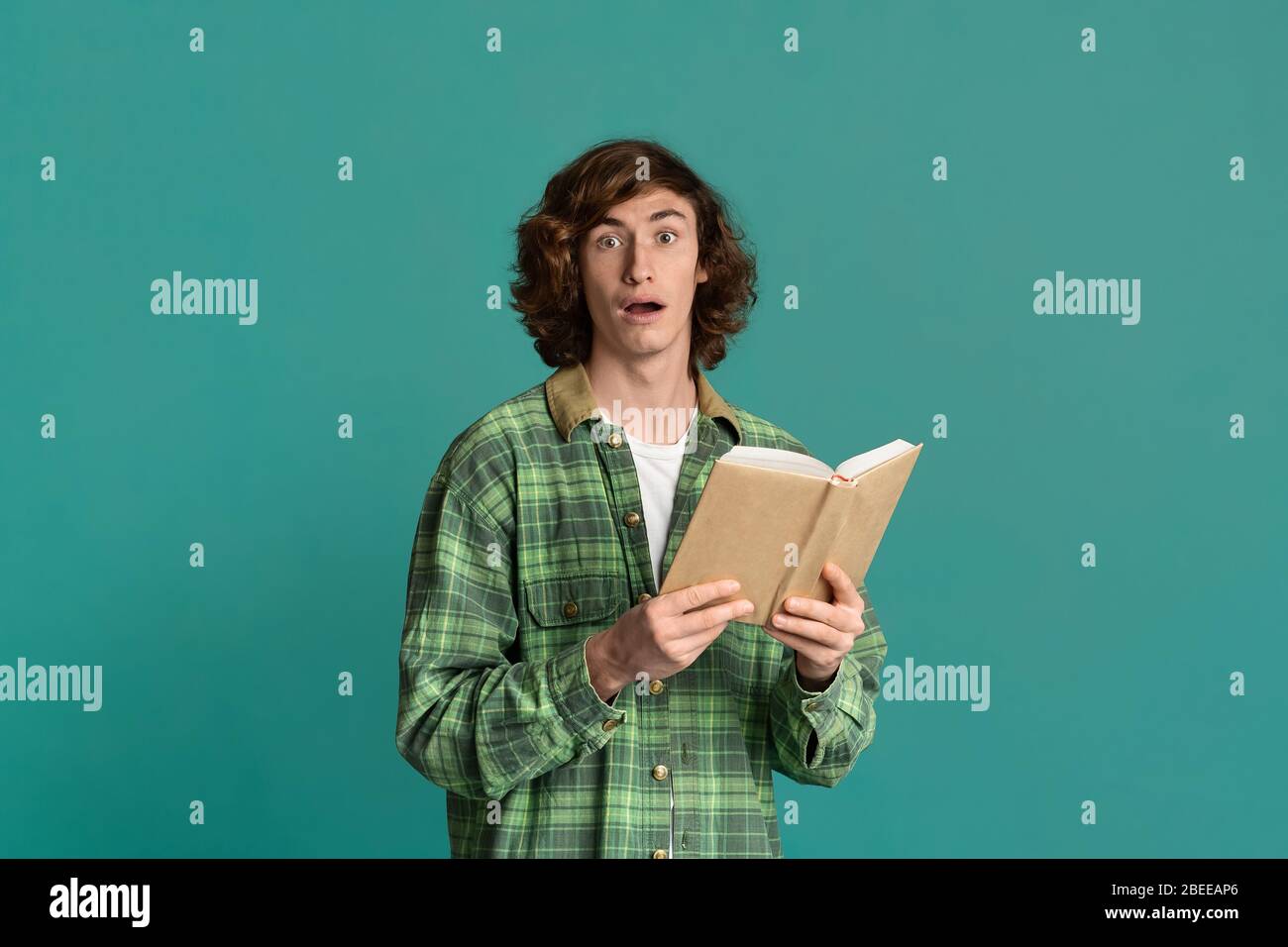 Bildungskonzept. Betäubt Teenager mit offenem Buch auf farbigem Hintergrund Stockfoto