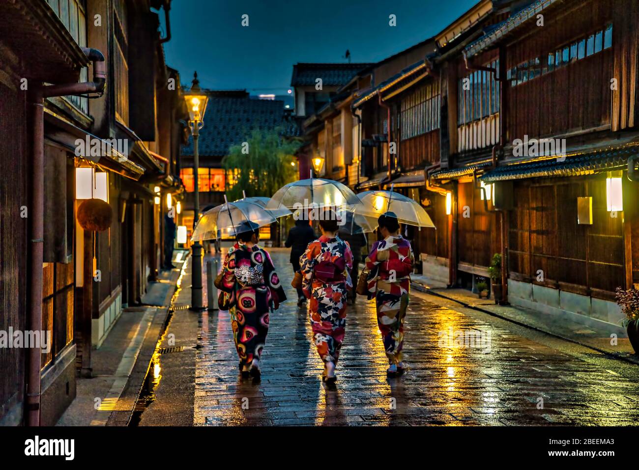 Frauen im traditionellen Kimono, die nachts im Higashi Chaya Viertel unter dem Regen in Kanazawa, Japan, spazieren. Stockfoto