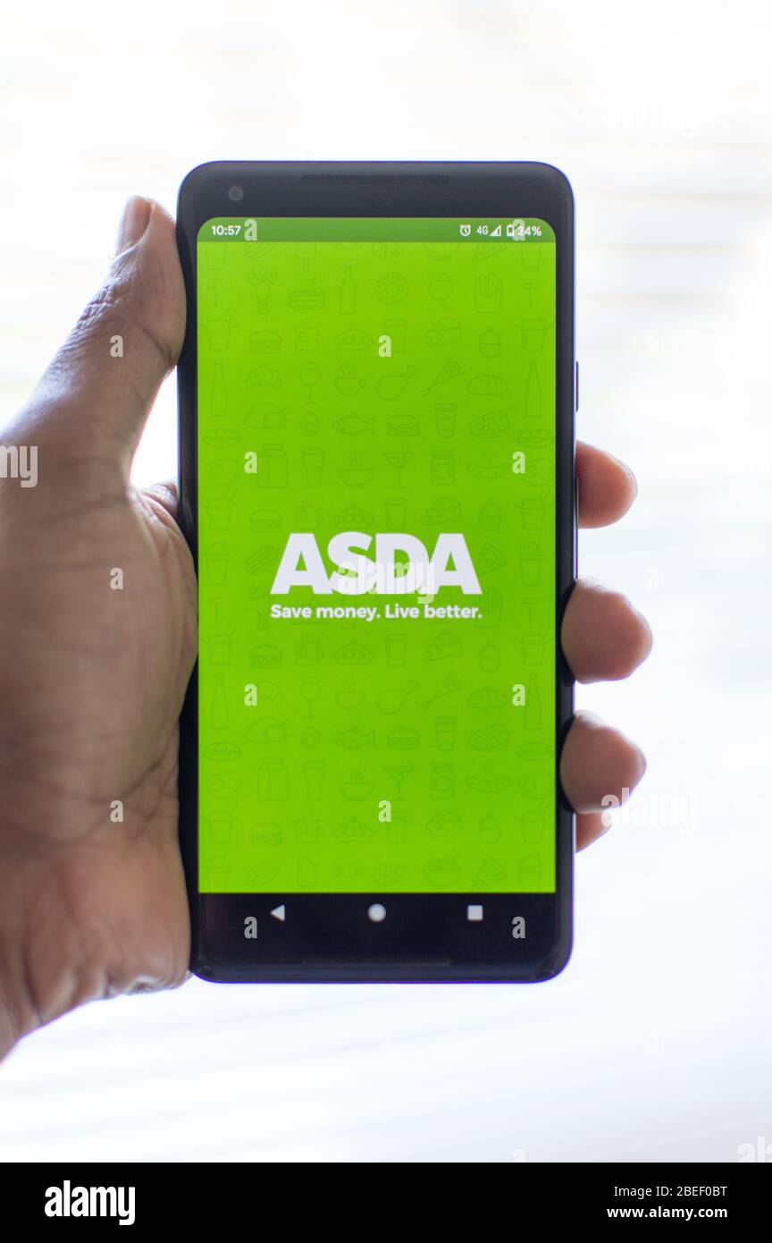 ASDA mobile App Laden auf einem Telefon von asiatischen Mann gehalten Stockfoto