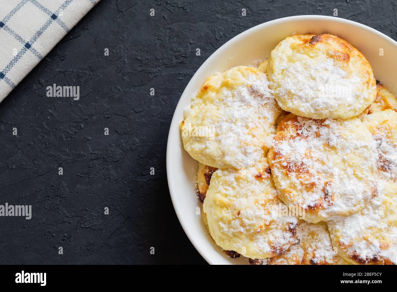 Süße Quark-Pfannkuchen auf dunklem Hintergrund. Syrniki, Quark im Ofen gebacken. Kopierbereich. Stockfoto