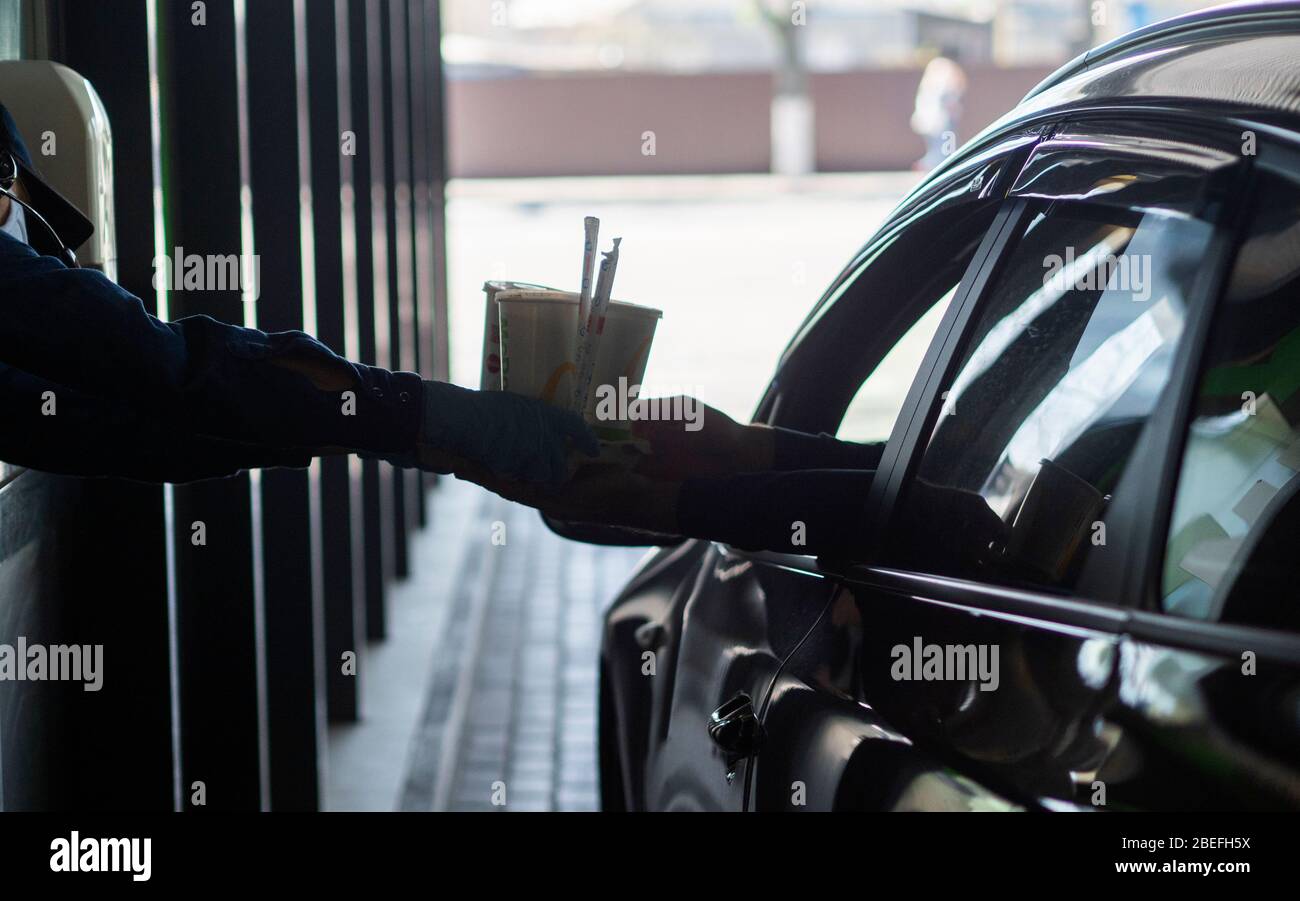 Der Fahrer durch das Fenster erhält Lebensmittel, die auf dem Mac Drive gekauft wurden. In der Ukraine wurde wegen der Pandemie des Coronavirus KOVID-19, die erhebliche Änderungen am Betrieb von Cafés und Restaurants vorgenommen, ein Notfall ausgerufen. Jetzt ist nur noch Essen über Kuriere oder Drive-in erlaubt. Stockfoto