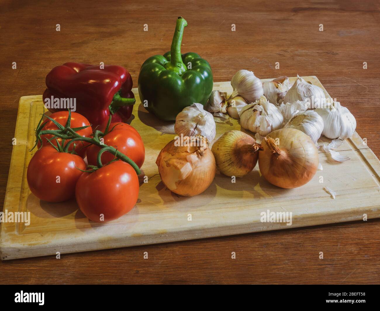 Gemüse auf dem Tisch. Grüner Pfeffer, roter Pfeffer, Knoblauch, Weintomaten und Zwiebeln Stockfoto