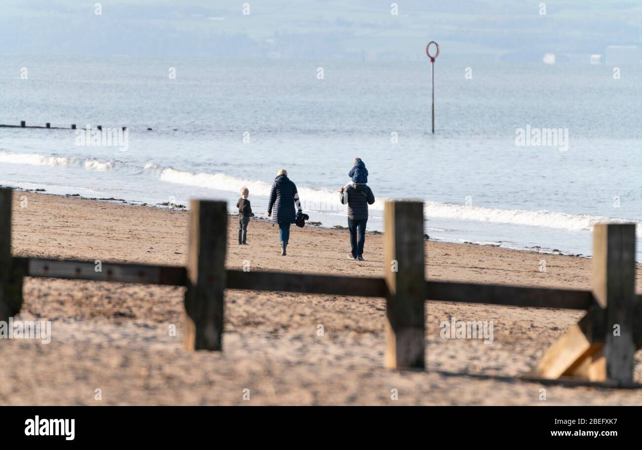 Portobello, Edinburgh, Schottland, Großbritannien. 13. April 2020. Menschen im Freien am späten Nachmittag am Strand von Portobello wandern und trainieren. Obwohl das Wetter sonnig war, war der Strand viel ruhiger als normal und die meisten Leute übten angemessene soziale Distanz. Iain Masterton/Alamy Live News Stockfoto