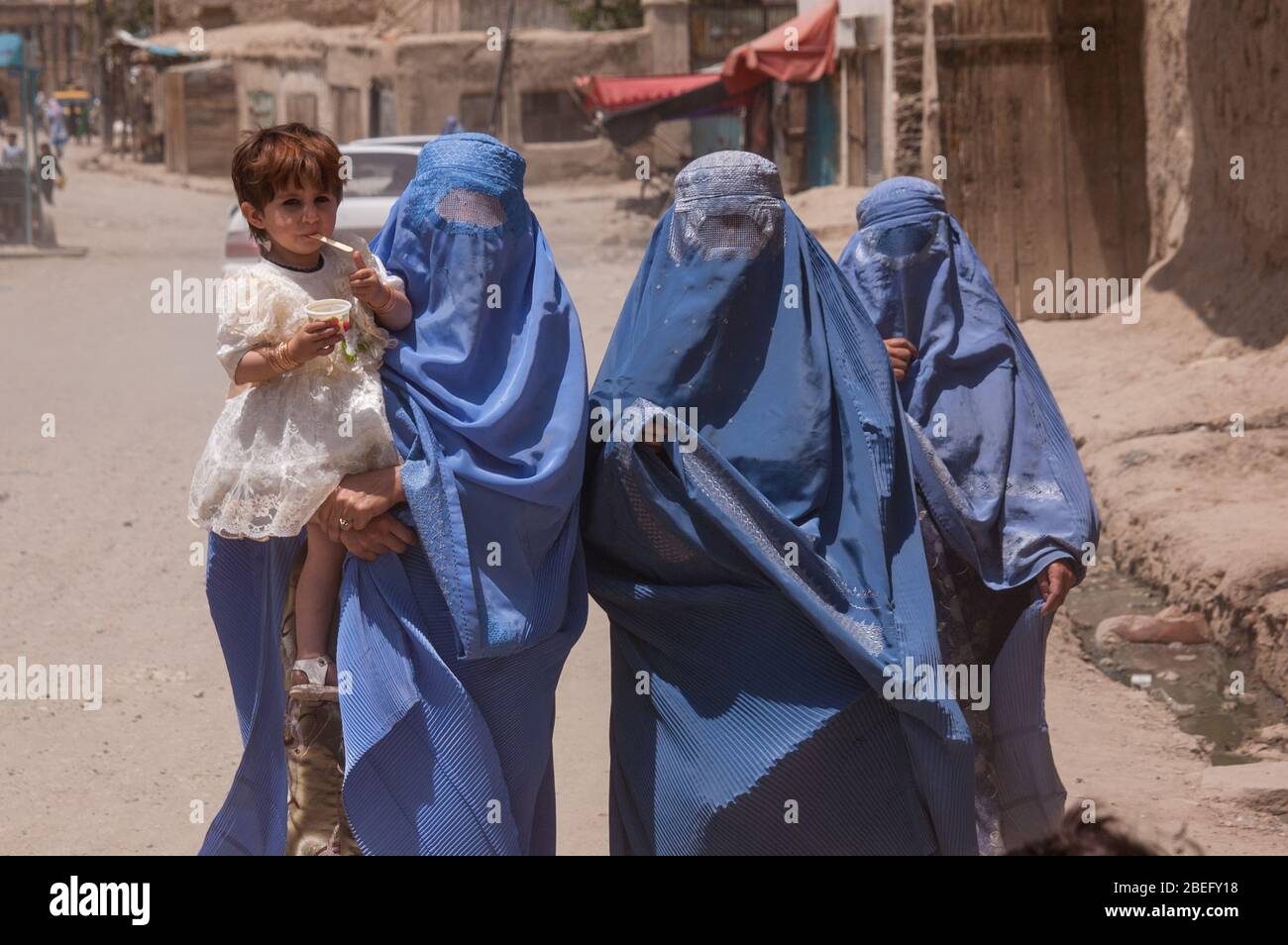 Frauen in Burkas in Kabul, die mit einem Kind gehen Stockfoto