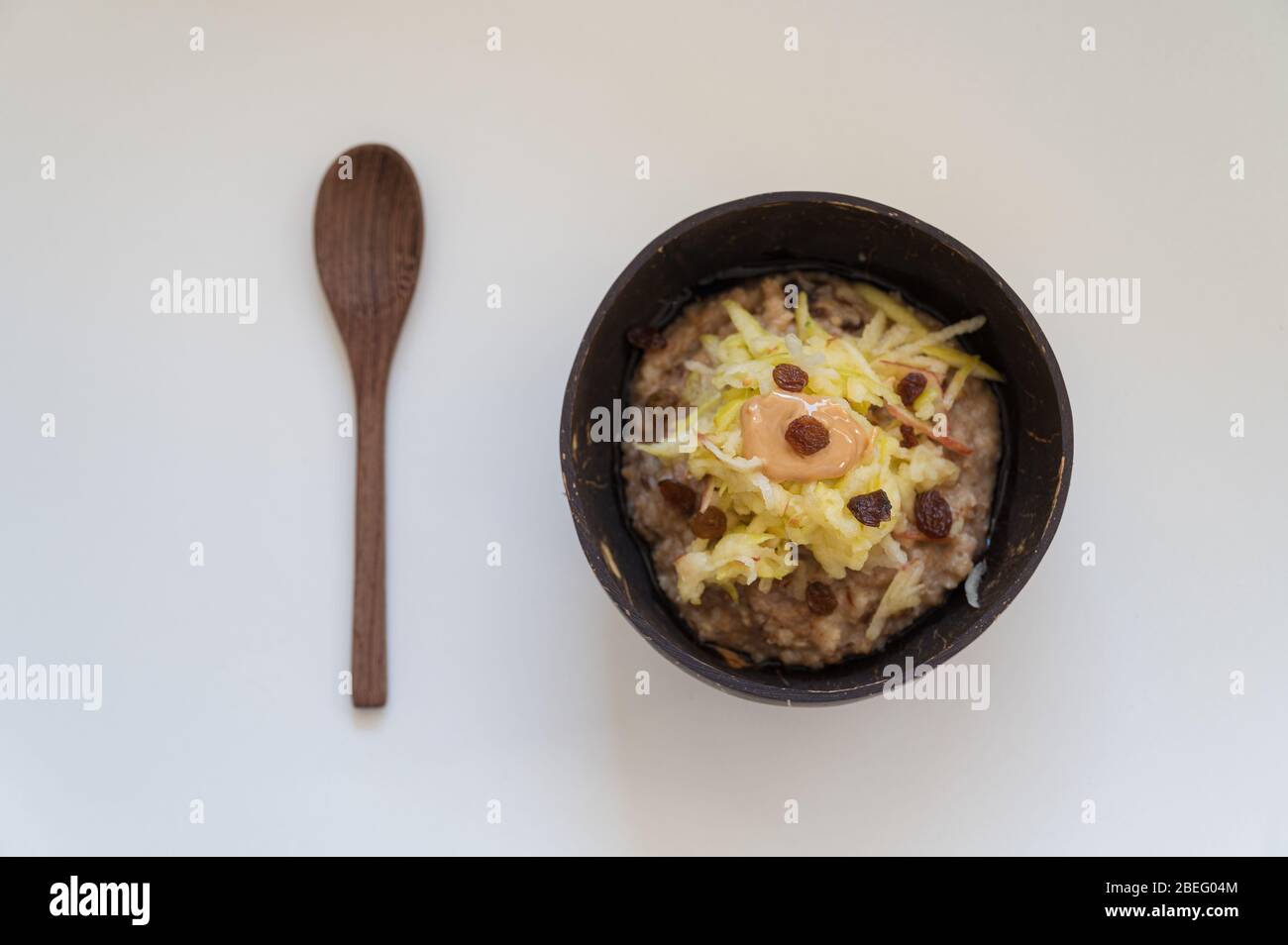 Draufsicht der köstlichen und nahrhaften veganen Frühstück Haferbrei Haferbrei mit geriebenem Apfel und Erdnussbutter, serviert in Kokosnussschüssel. Stockfoto