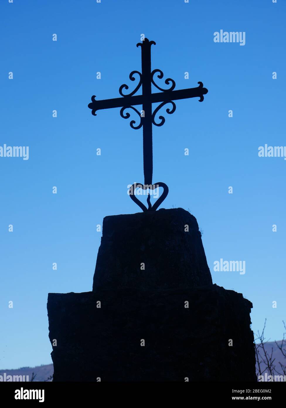 Schwarzes christliches Kreuz mit blauem Himmel im Hintergrund - Hochformat Stockfoto