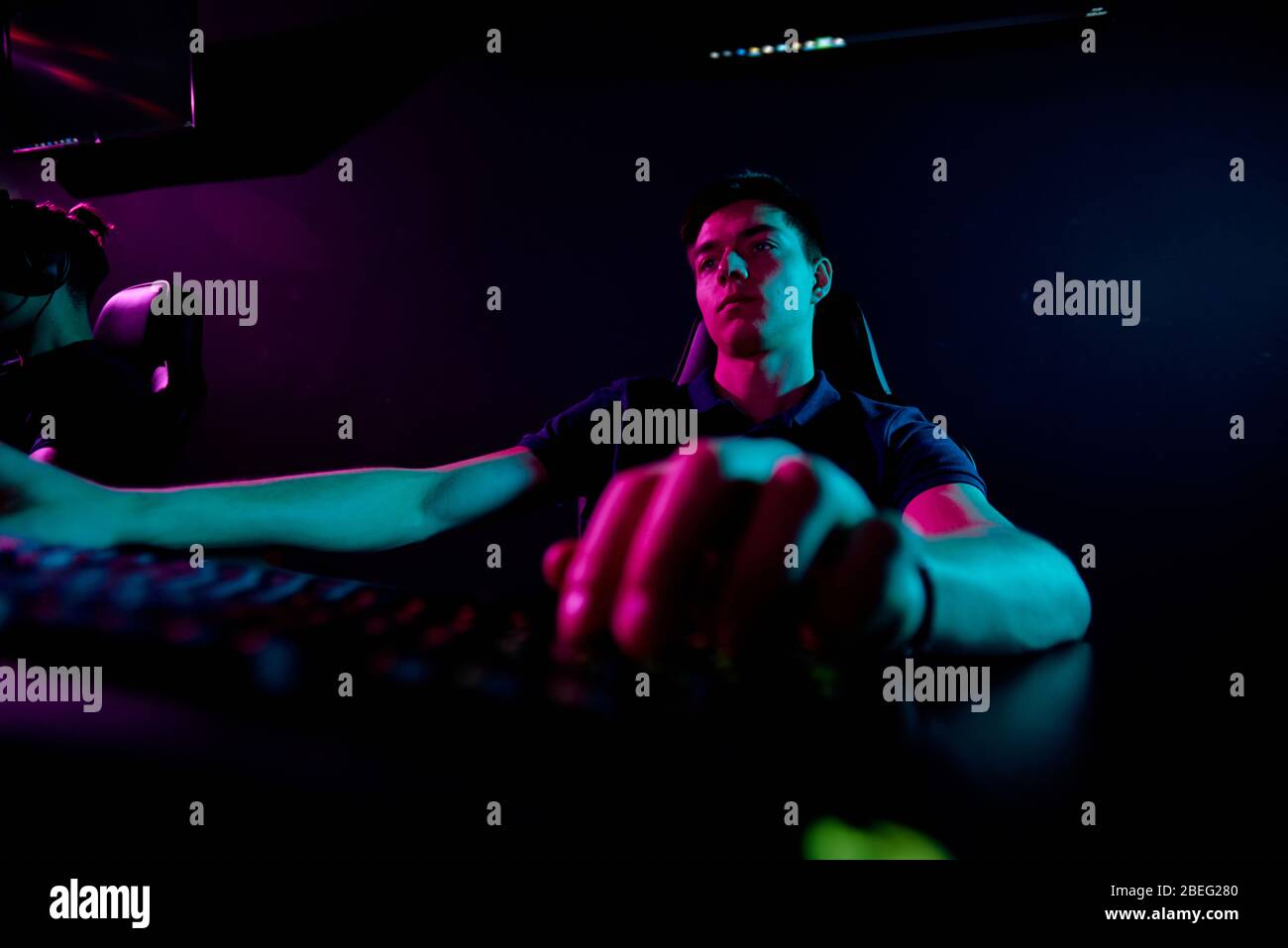 Ernst langweiligen jungen Mann sitzt am Tisch und spielen Videospiel oder Codierung Skript für neue App Stockfoto