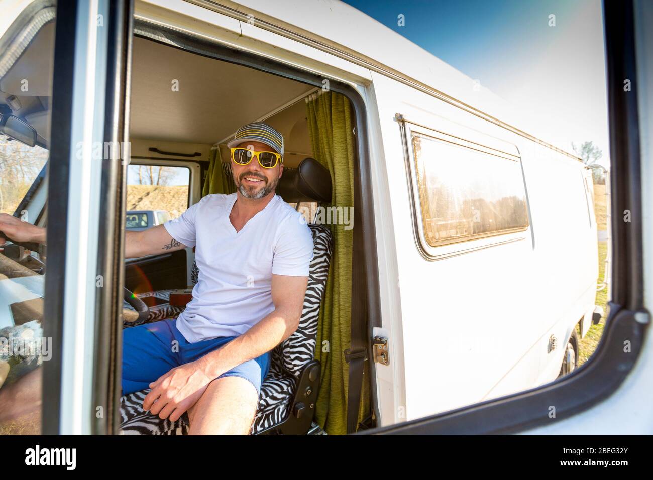 Porträt eines Mannes mit Sonnenbrille während der Ferien in seinem Van Stockfoto