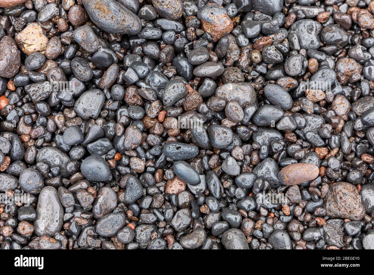 Glänzende schwarze Steine an der Küste in Hana, Hawaii Stockfoto