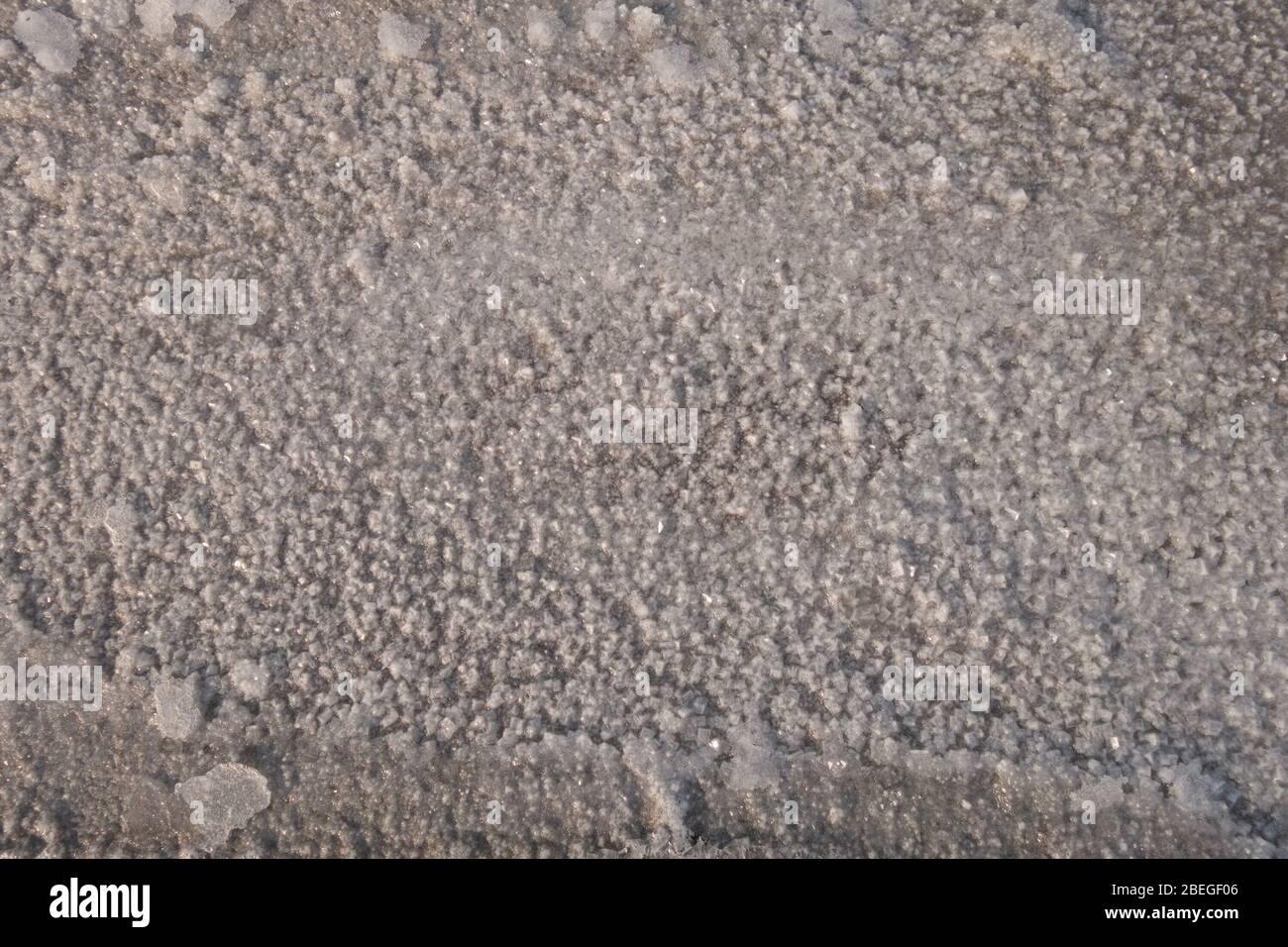 Sandiger Boden des getrockneten Reservoirs mit den Rissen und den Salzkristallen. Stockfoto