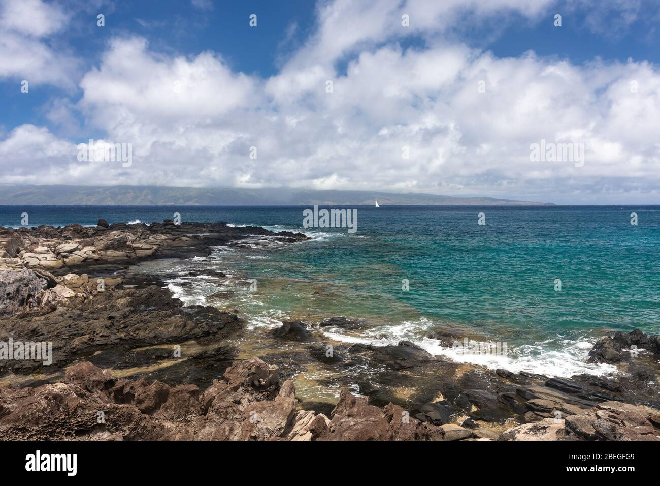 Segelboot vor der felsigen Küste des Kapalua Küstenweges von Maui, Hawaii Stockfoto