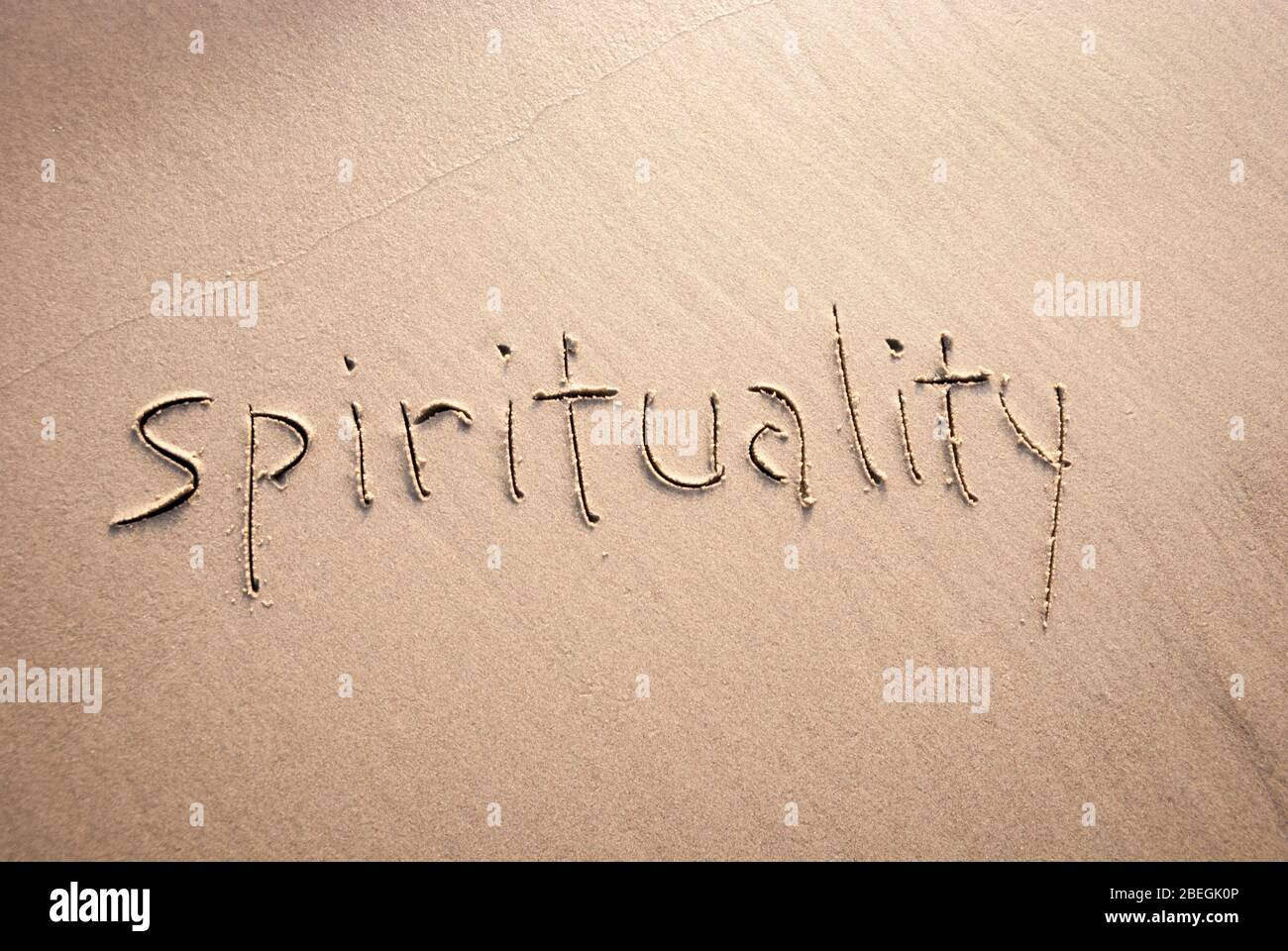 Einfache nicht konfessionelle Spiritualität Nachricht handgeschrieben in Kleinbuchstaben auf texturierten Sandstrand Stockfoto