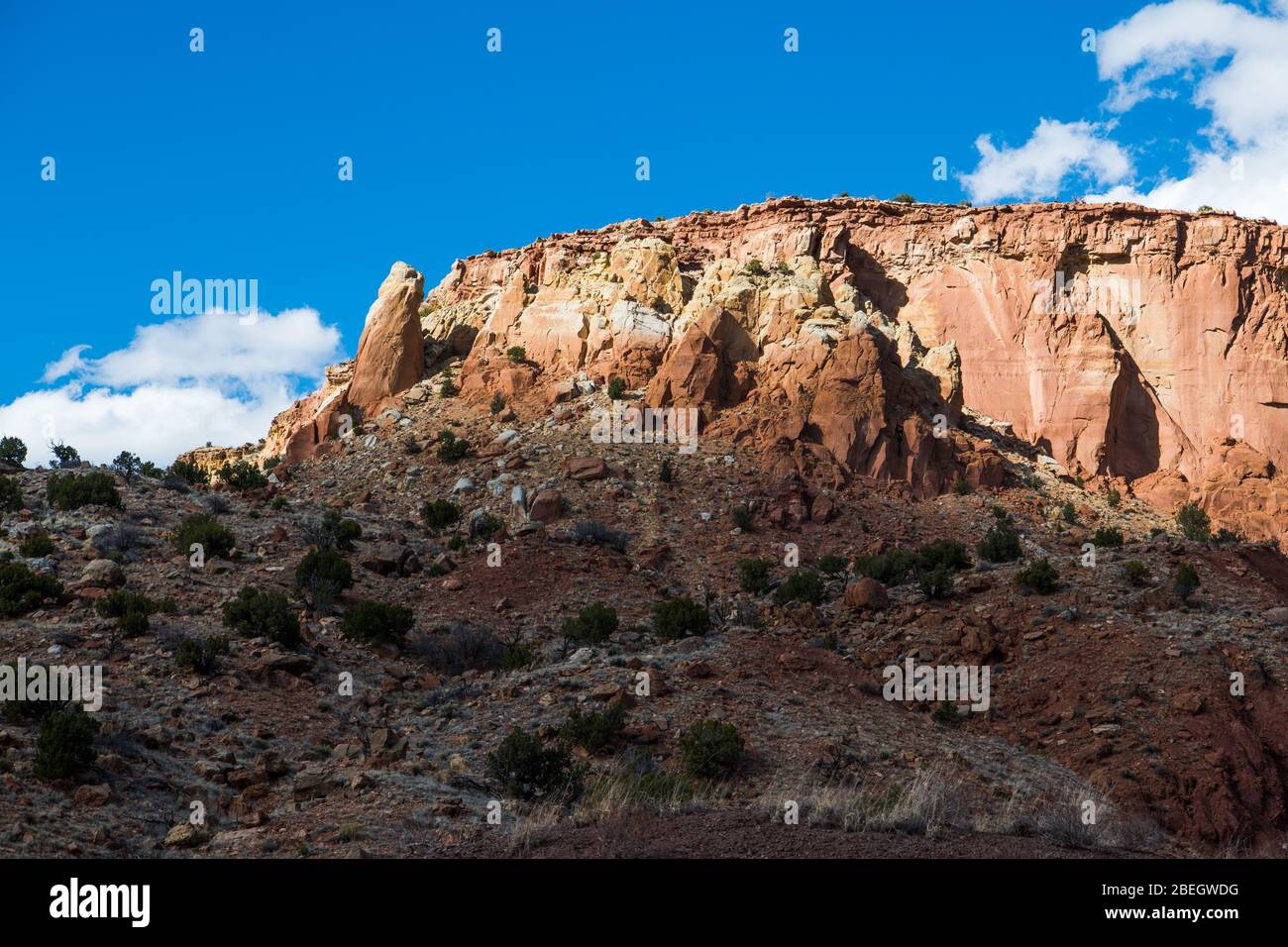 Eine bunte Wüste mesa mit Sandsteinfelsen und hohen Klippen von der Sonne durch eine Pause in den Wolken im Norden von New Mexico beleuchtet Stockfoto