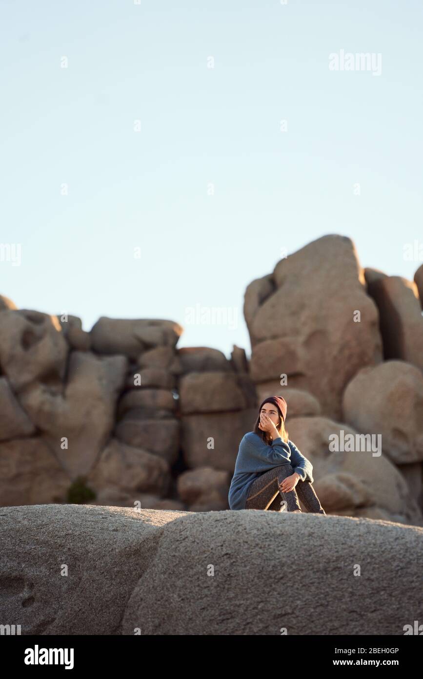 Junge Frau auf Felsen sitzend, nachdenkend Stockfoto