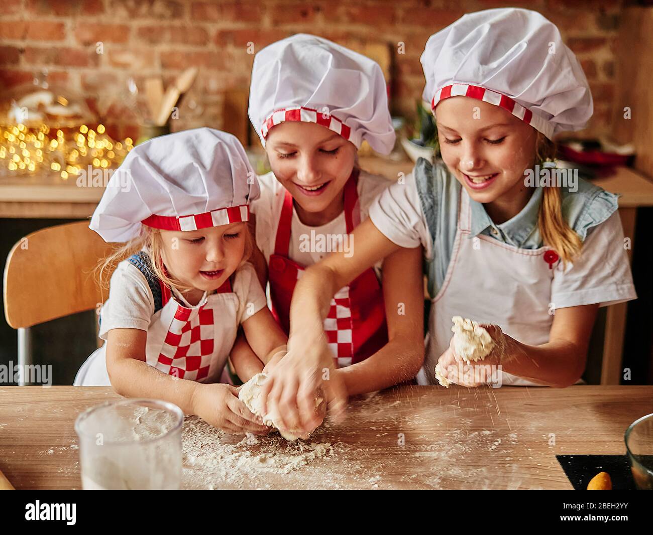 Drei kleine Köche genießen in der Küche Kuchen zu machen. Mädchen in der Küche. Haushaltung für Familien Stockfoto