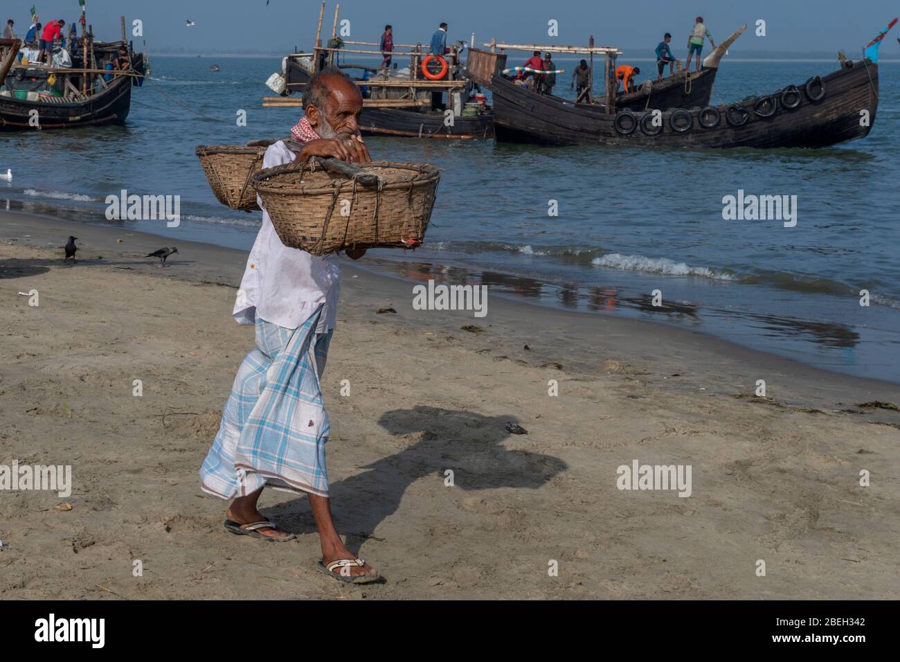 Älterer Mann, der leere Fischkörbe in einem Fischerdorf nördlich von Cox's Bazar trägt Stockfoto