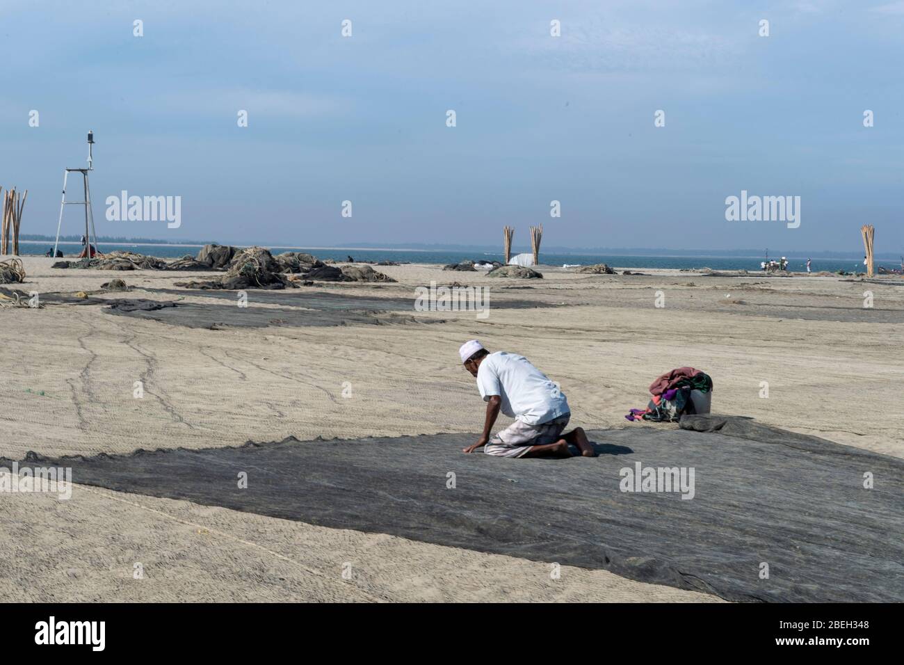 Zwei Männer beten auf einem Fischernetz in einem Fischerdorf nördlich von Cox's Bazar Stockfoto