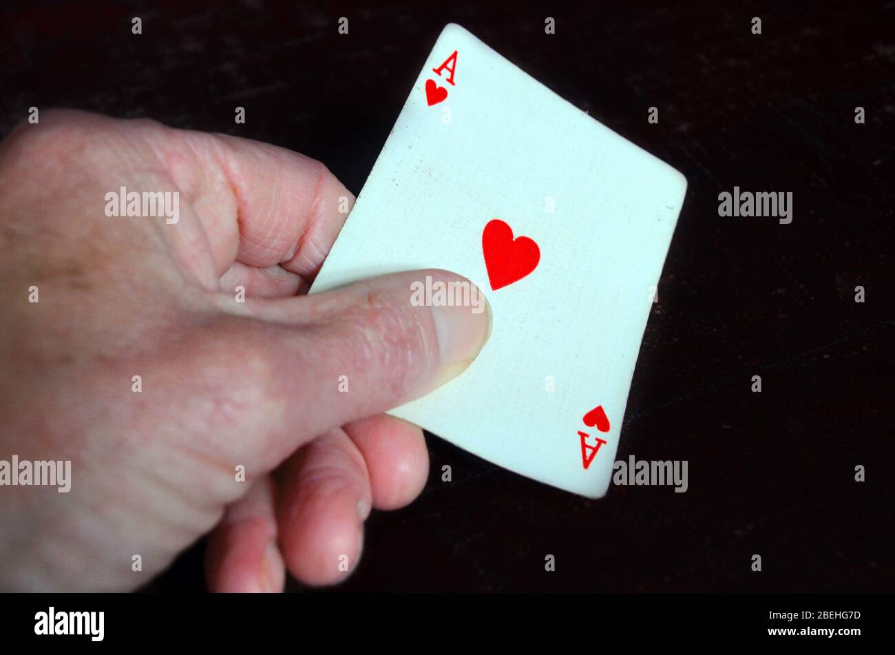 Person, die das rote Herz-Ass in der Hand hält. Stockfoto